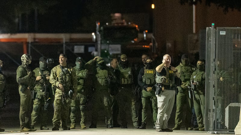 Federal law enforcement officers stand guard in the open gate of the fence built on Beach...