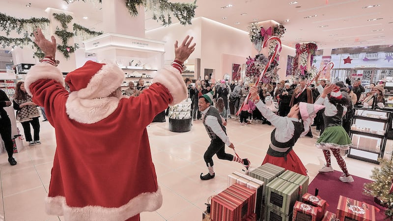Personas que representan a Santa Claus y sus elfos actúan en el departamento de cosméticos de...