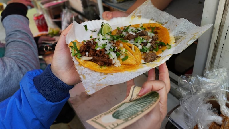 Un ciclista recibe comida de la vendedora ambulante Yulisa Robles, derecha, en Gage Park...