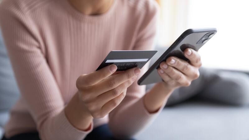 Close up female hands holding credit card and smartphone, young woman paying online, using...