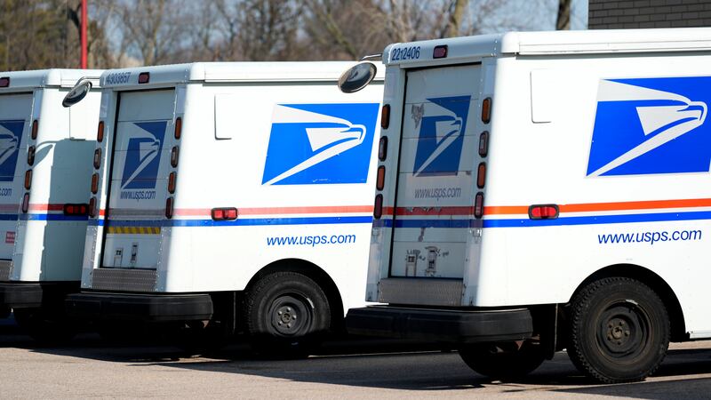 FILE - U.S. Postal Service trucks park outside a post office in Wheeling, Ill., Monday, Jan....