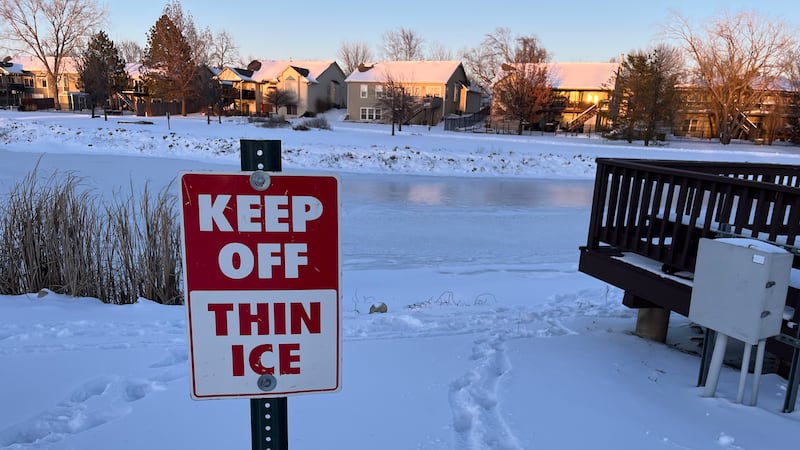 "Keep off: Thin Ice" Written on a sign in front of a frozen body of water.