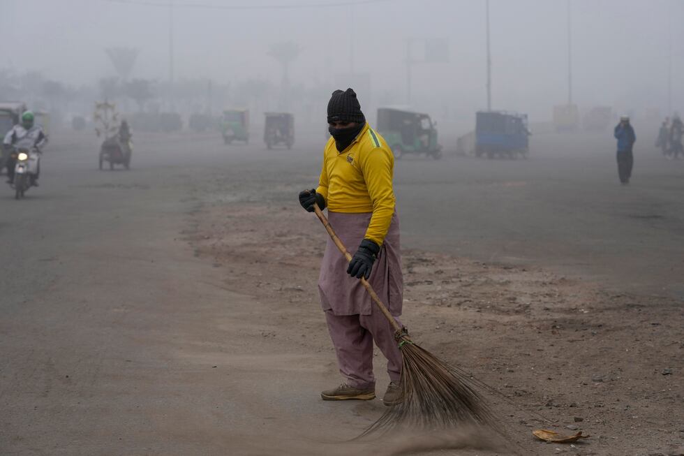 ARCHIVO - Un barrendero limpia en medio del smog que reduce la visibilidad en Lahore,...