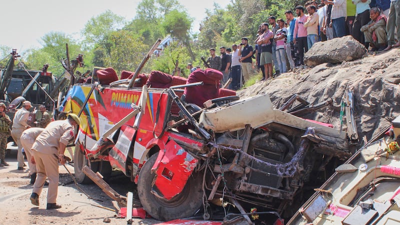Policías inspeccionan los restos de un autobús de pasajeros que se precipitó por una ladera al...